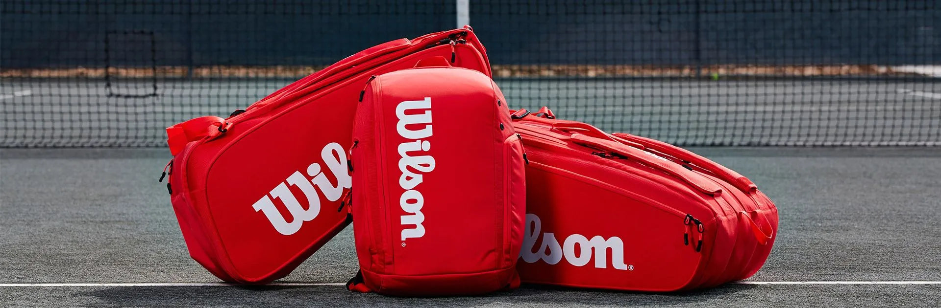 Wilson tennis bags and backpacks on a tennis court