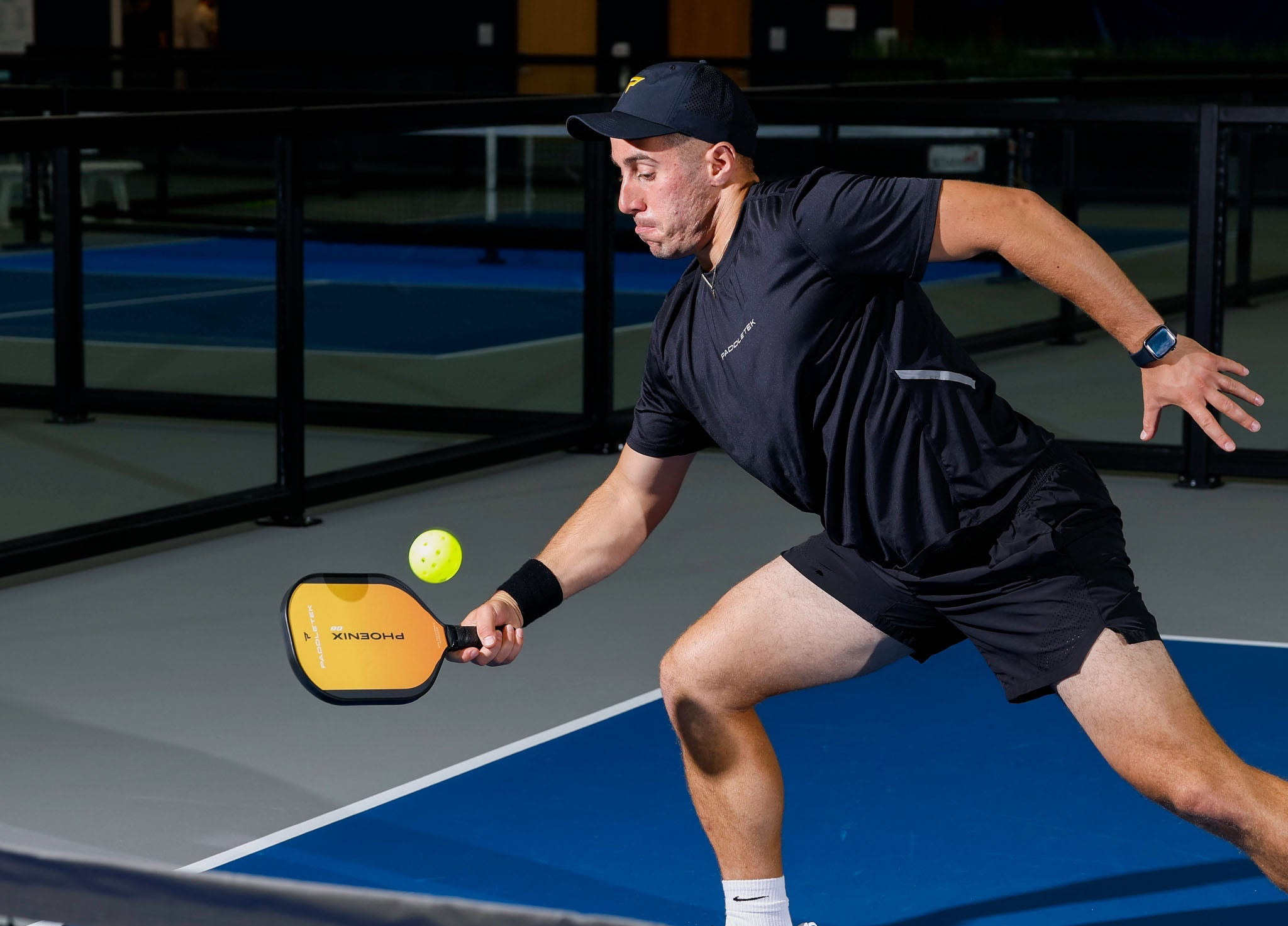 Man playing pickleball on an indoor court, holding a paddle and ball.