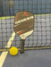Austrani Genesis Power Pickleball Paddle and a pickleball at the net